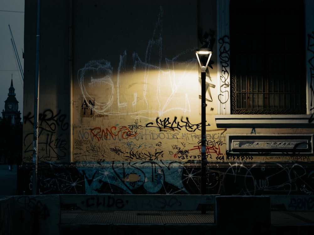 a street light sitting next to a wall covered in graffiti