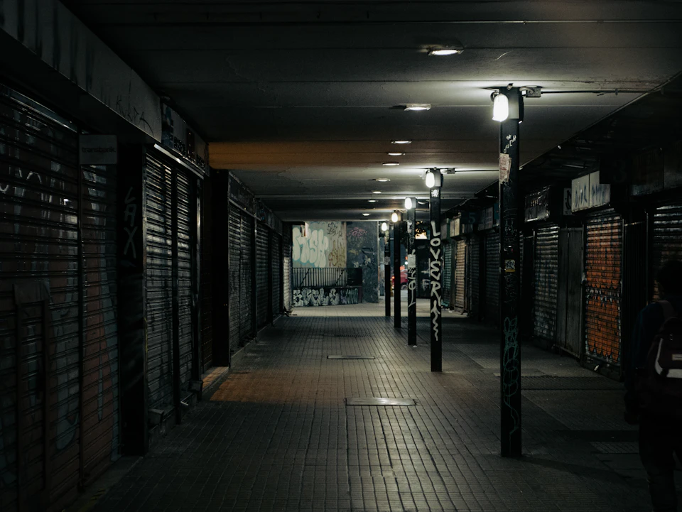 Dimly lit shopping mall with closed shops and graffiti-covered walls along its perimeter