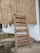 A wooden signboard is propped against a bamboo wall. The sign lists offerings such as vegetarian/vegan food, South Indian fare, speciality coffee, juices, smoothies, hemp experiments, and displays the hours of operation from 9 AM to 10 PM daily.