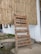 A wooden signboard is propped against a bamboo wall. The sign lists offerings such as vegetarian/vegan food, South Indian fare, speciality coffee, juices, smoothies, hemp experiments, and displays the hours of operation from 9 AM to 10 PM daily.