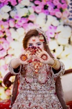 a woman in a wedding dress holding her hands up to her face