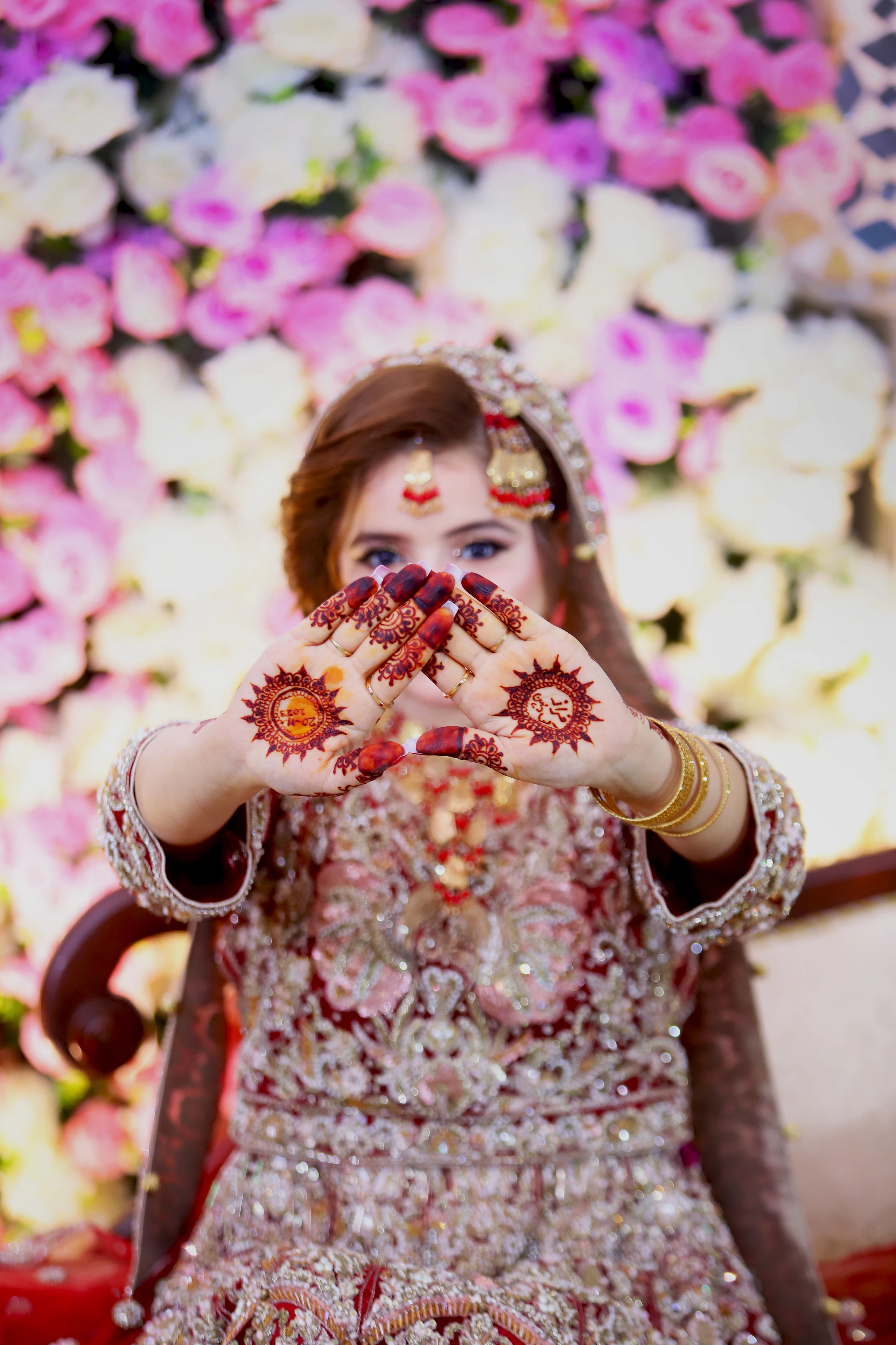 Bride showing henna against a floral backdrop