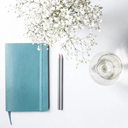 Close-up of a journal and pen on a pastel-colored table, symbolizing clarity.