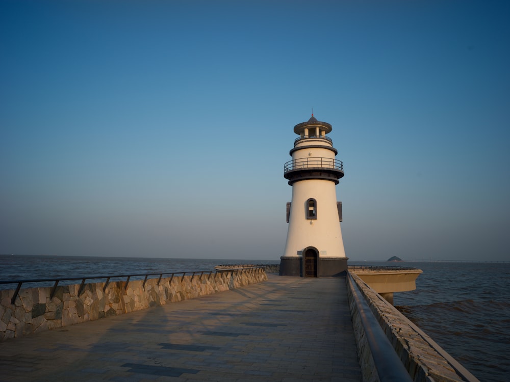 um farol sentado em cima de um píer ao lado do oceano