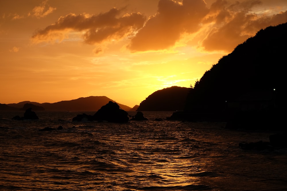 a sunset over a body of water with mountains in the background