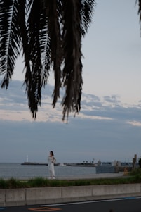 Portrait of Gwendolyn Bilboat standing by a Palm Coast waterfront home with palm trees and bright sunlight.