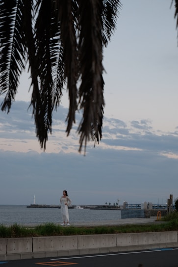 Portrait of Gwendolyn Bilboat standing by a Palm Coast waterfront home with palm trees and bright sunlight.