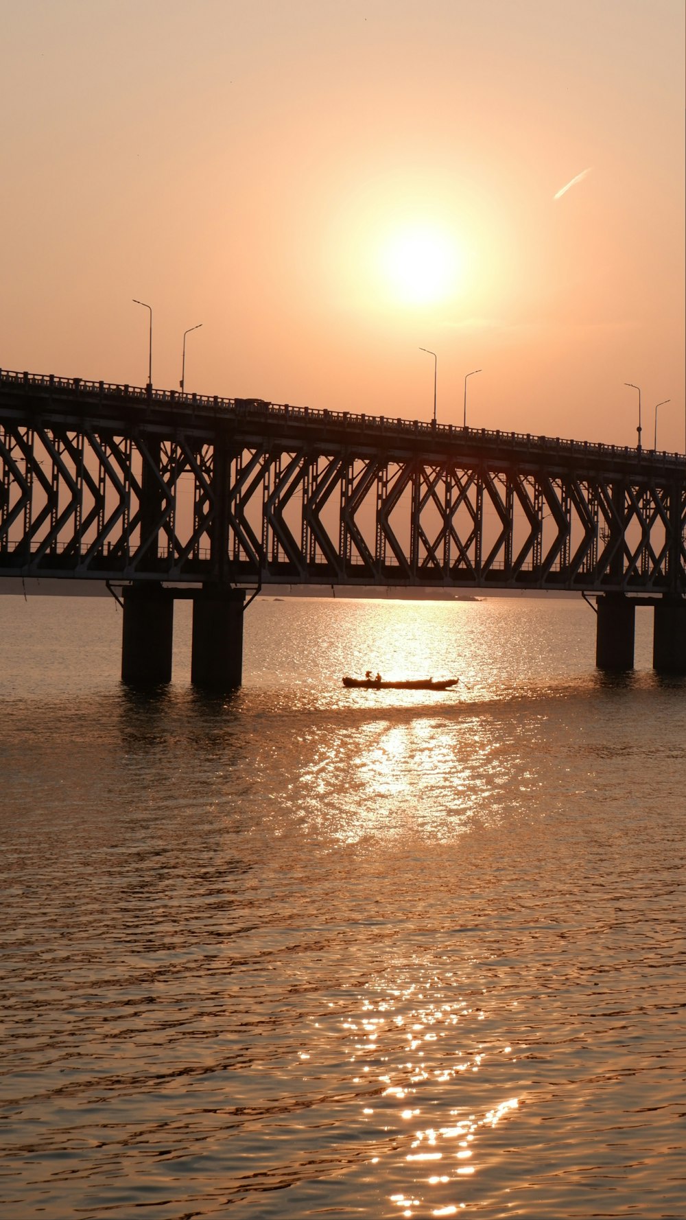 the sun is setting over a bridge over a body of water