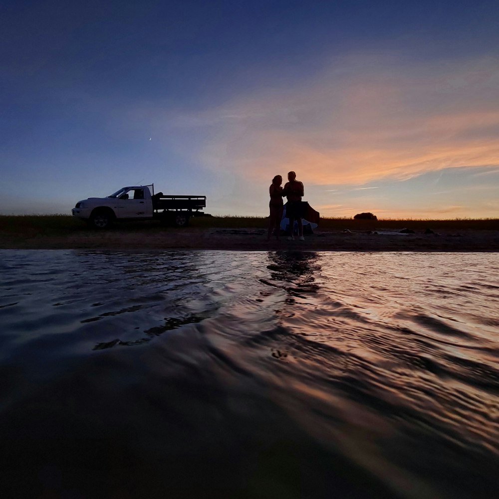 a couple sitting on the back of a truck in the water