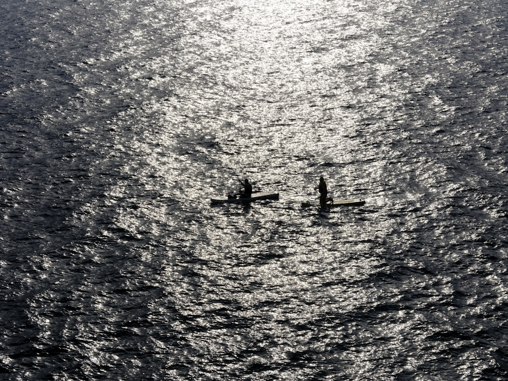 two people in a canoe in the middle of the ocean