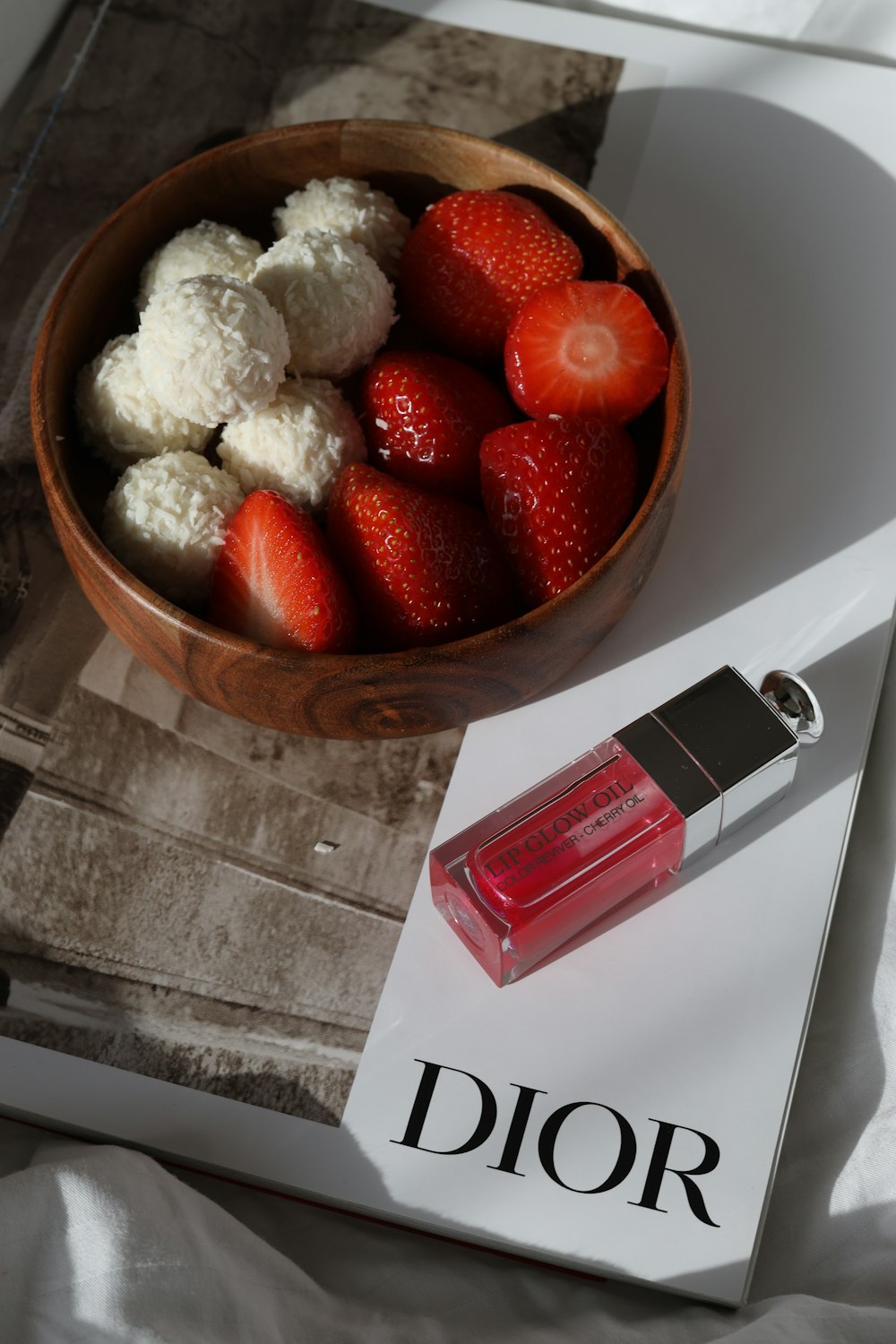 a bowl of strawberries and a bottle of dior