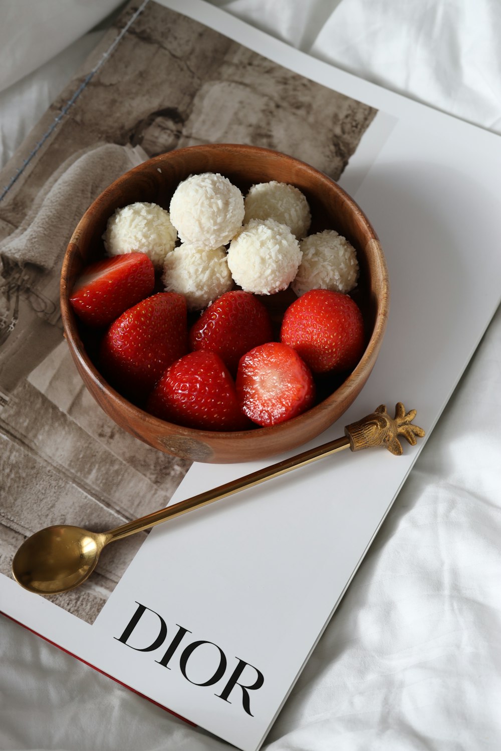 a bowl of strawberries on a table with a spoon