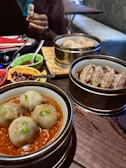 Artfully arranged dim sum baskets with steam rising, set on a red and gold tablecloth.