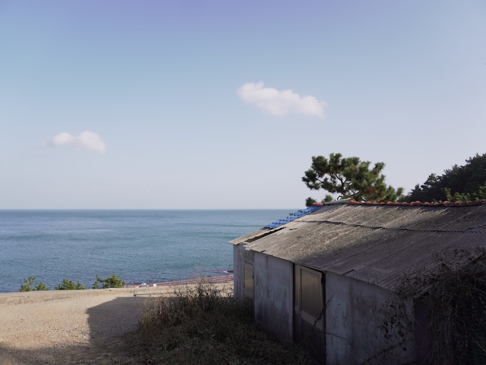 an old shack sitting on a beach next to the ocean