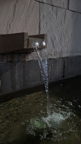 a water fountain spewing water into a pool of water