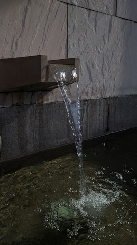 a water fountain spewing water into a pool of water