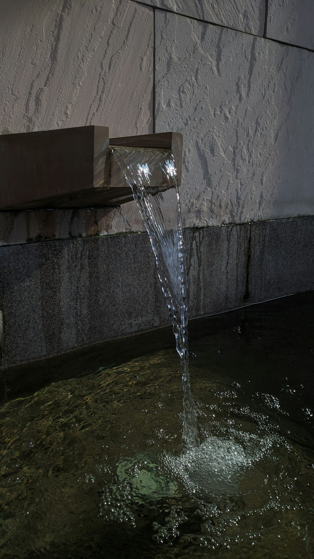 a water fountain spewing water into a pool of water
