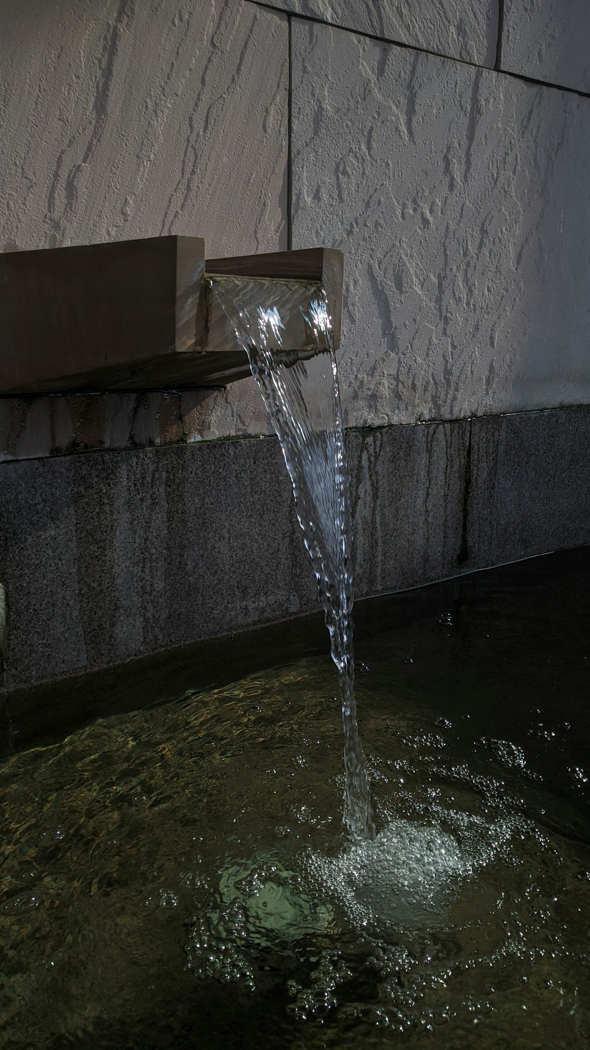 A water fountain spewing water into a pool of water