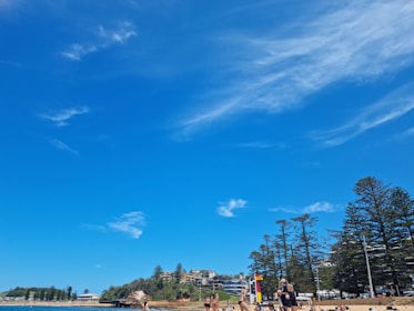 A sunny beach scene in Qingdao with families enjoying the shore and blue skies.