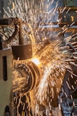 Close-up of a bending machine shaping a metal sheet with sparks flying gently.