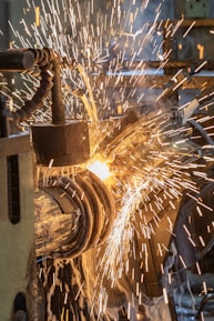 Close-up of sheet metal fabrication process with sparks flying.