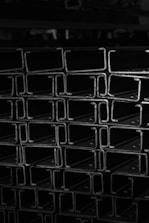 High-contrast black and white image of steel beams being loaded for delivery.