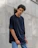 A candid photo of a young man wearing a deep navy hoodie from navycrew, standing against an urban graffiti wall.