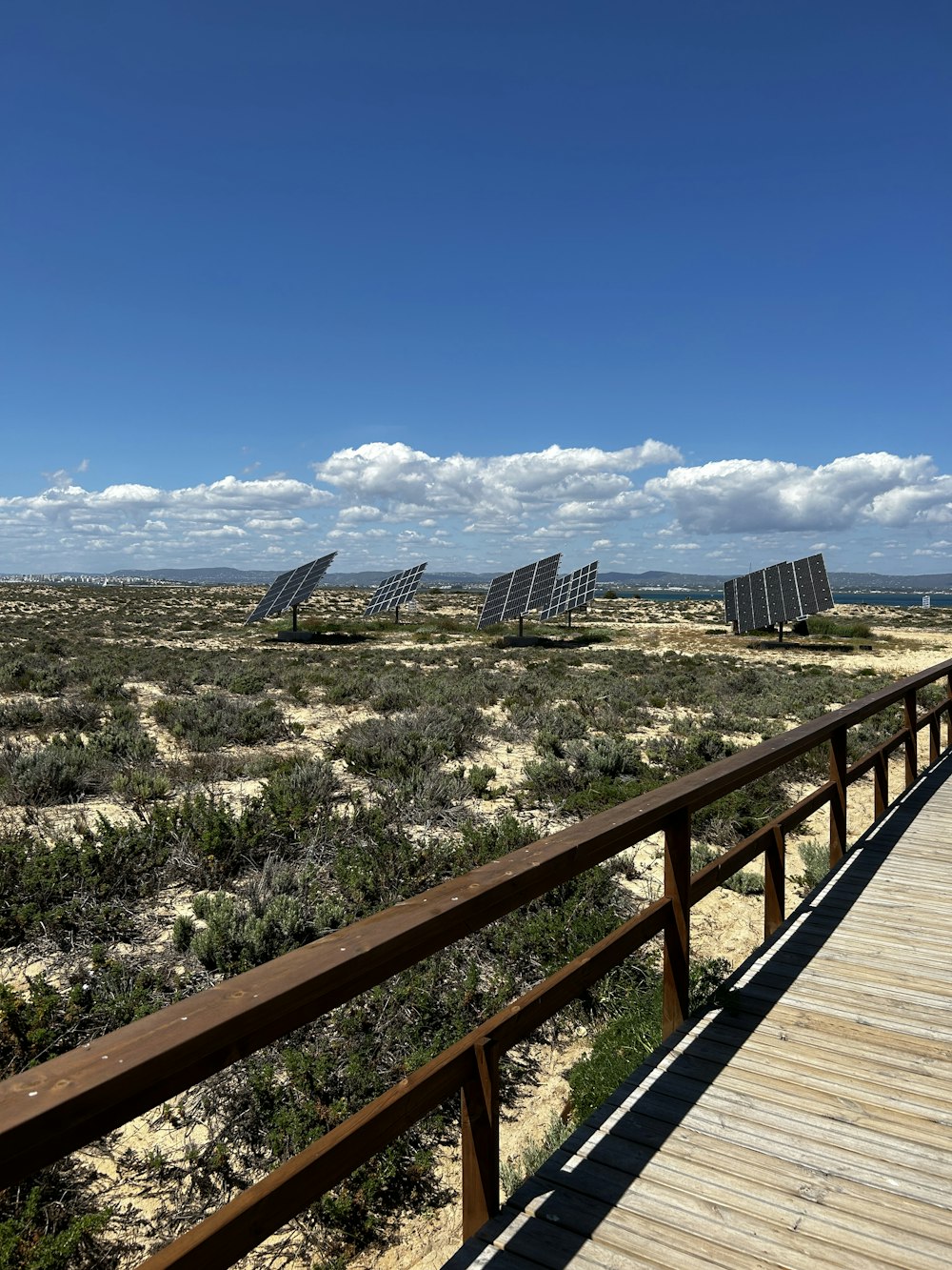 a wooden walkway with solar panels in the distance