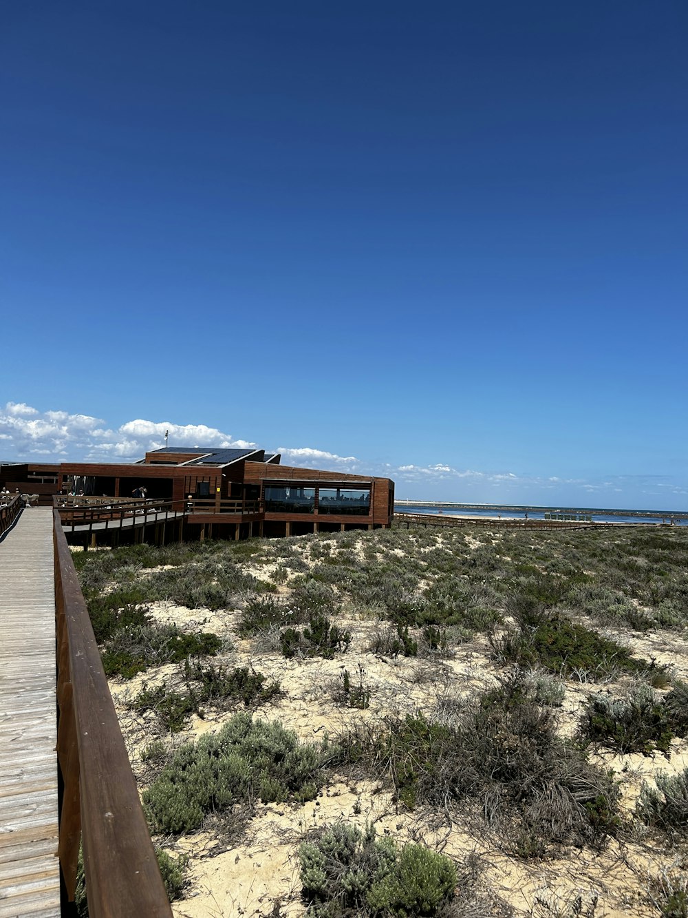 a wooden walkway leading to a building on the beach