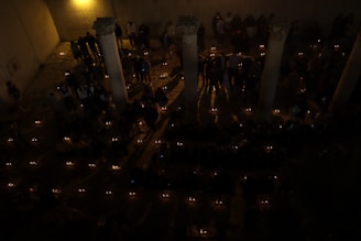 A group of people lighting memorial candles in a peaceful outdoor environment.