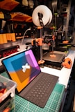 A vibrant workspace showing colorful notebooks, a calculator, and a 3D printer in action.