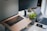 A workspace setup featuring a laptop with its screen slightly open, a tablet, a smartphone, and a wireless keyboard on a desk. A potted green plant adds a touch of nature to the sleek and modern tech environment. Multi-screen setup suggests a focus on productivity.