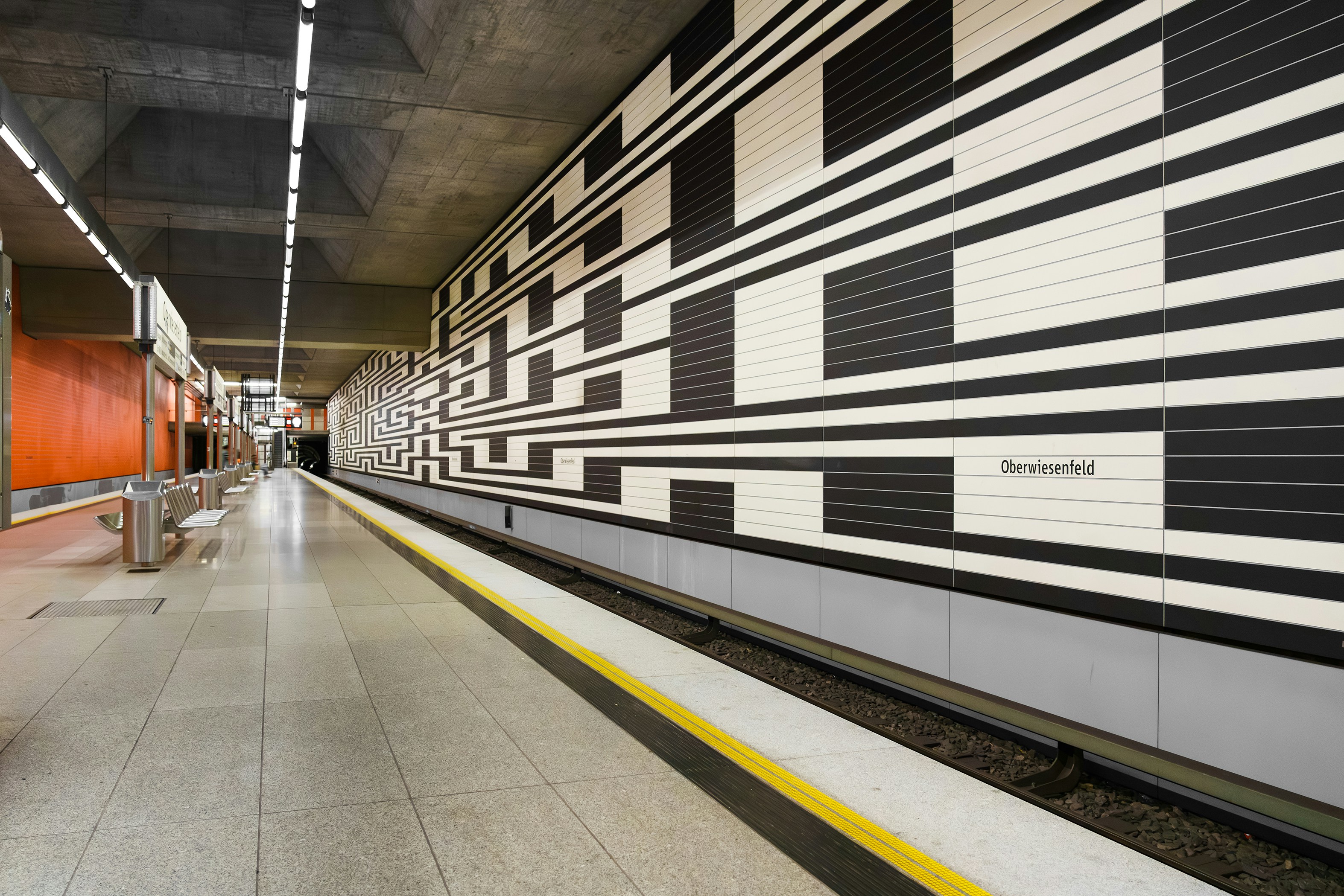 A Munich U-Bahn train pulling into a tiled underground platform