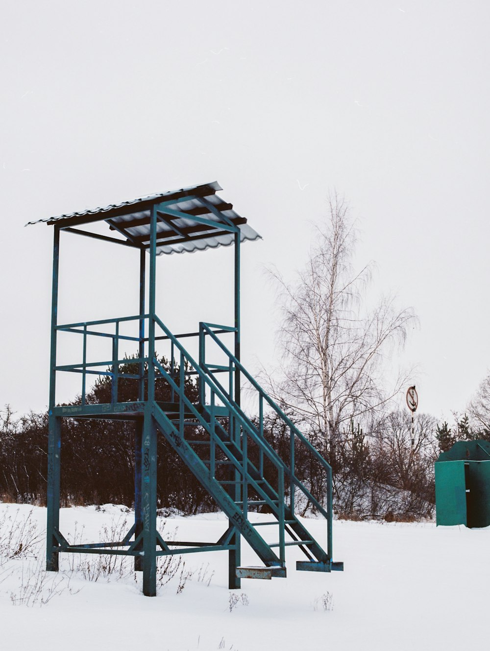 a small metal structure in the middle of a snowy field