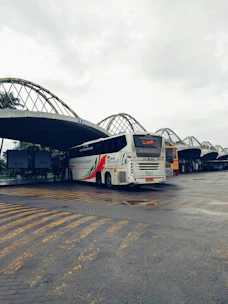 A modern red passenger bus parked at a clean station with clear signage.