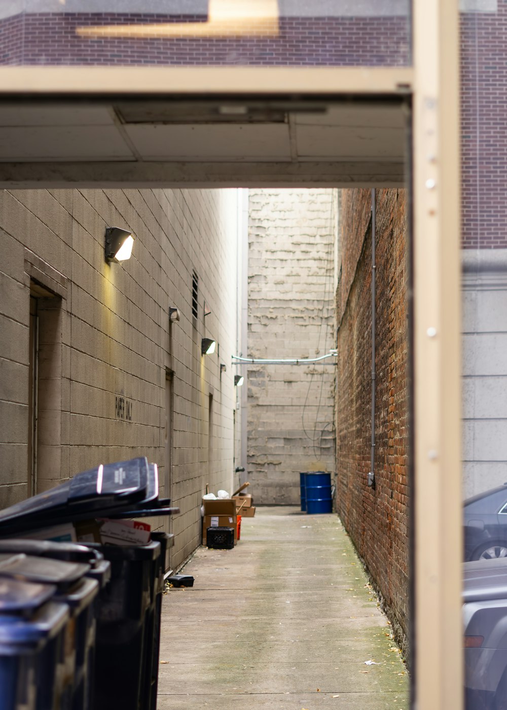 a narrow alley way with garbage cans on the side