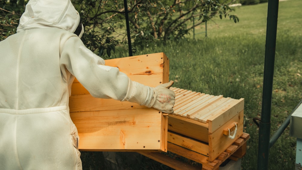a person in a white robe holding a beehive