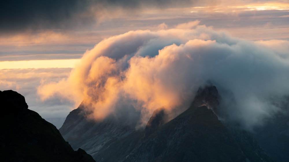 a mountain covered in clouds at sunset