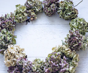 Soft terracotta and charcoal funeral wreath resting gently on a wooden table.