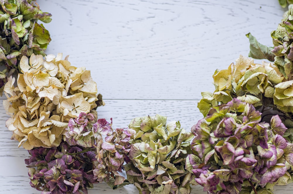 a wreath of dried flowers on a white wooden background