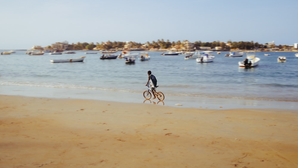 a man riding a bike on top of a sandy beach