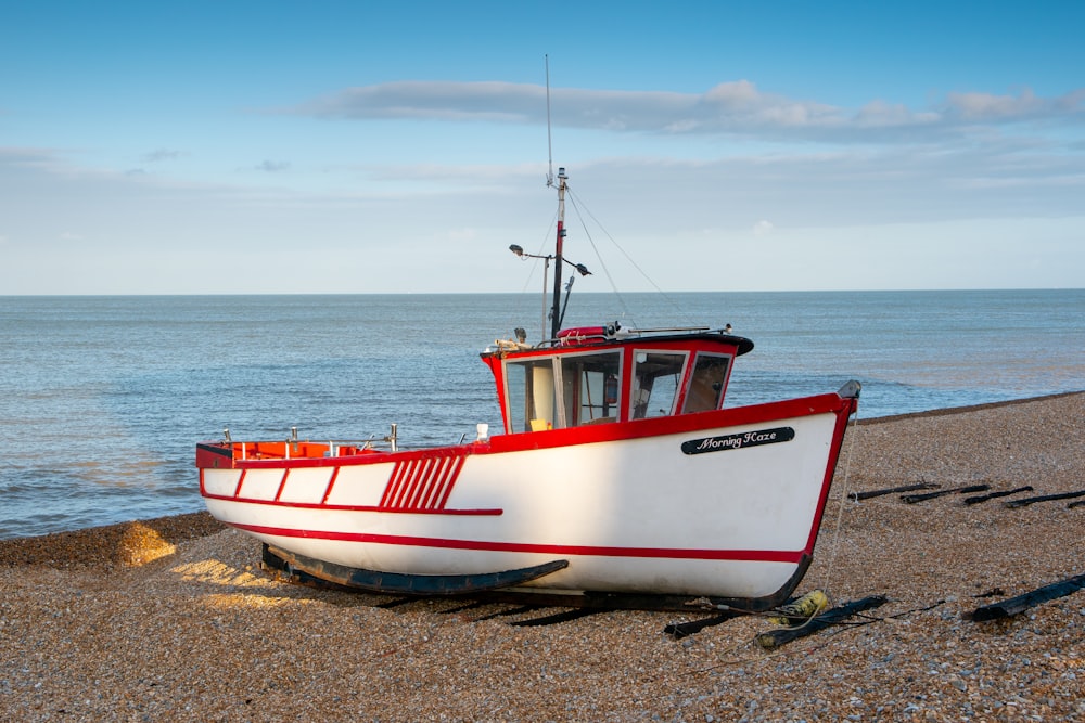 a red and white boat sitting on top of a beach