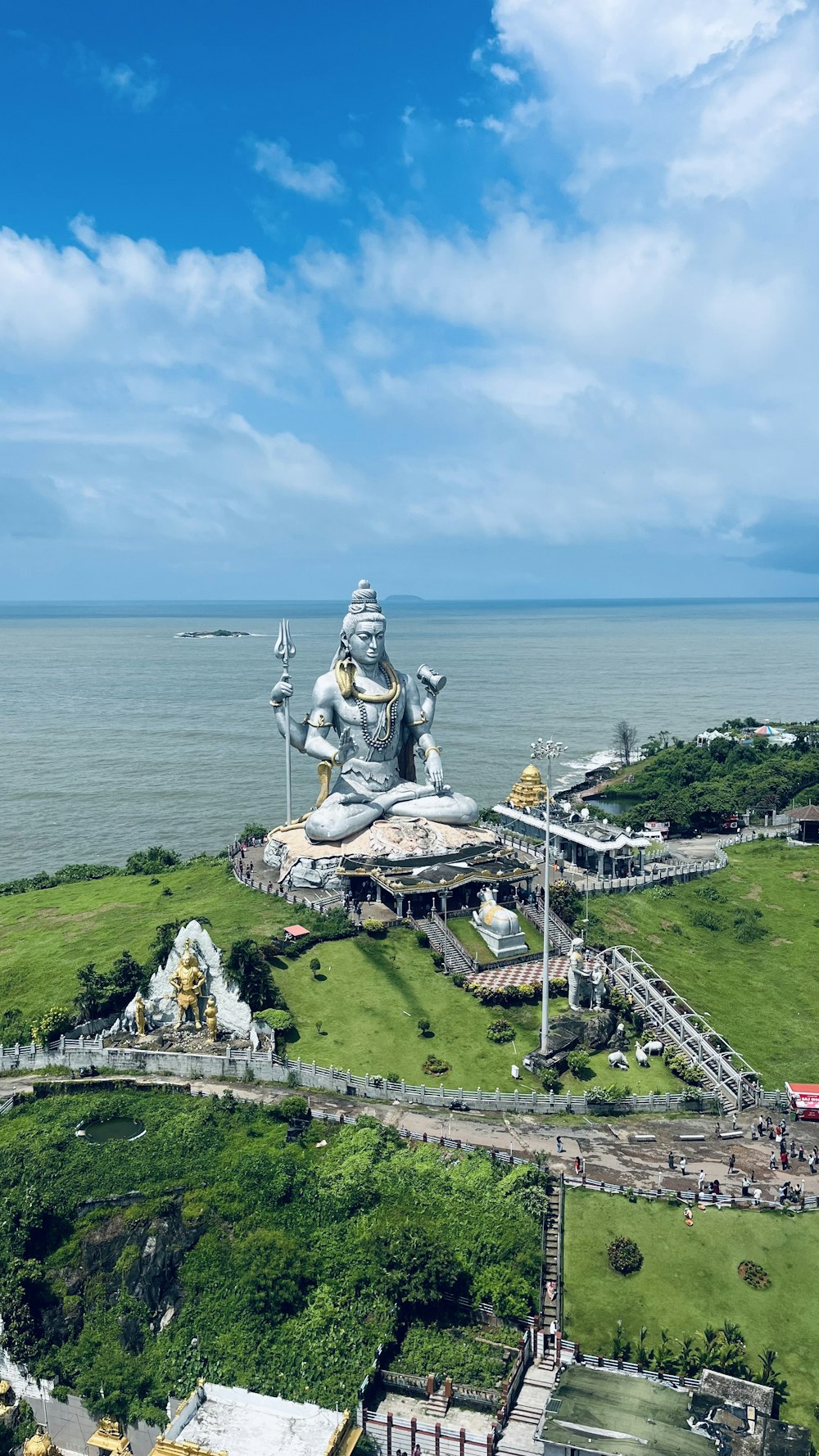 a large statue of a person sitting on top of a lush green hillside