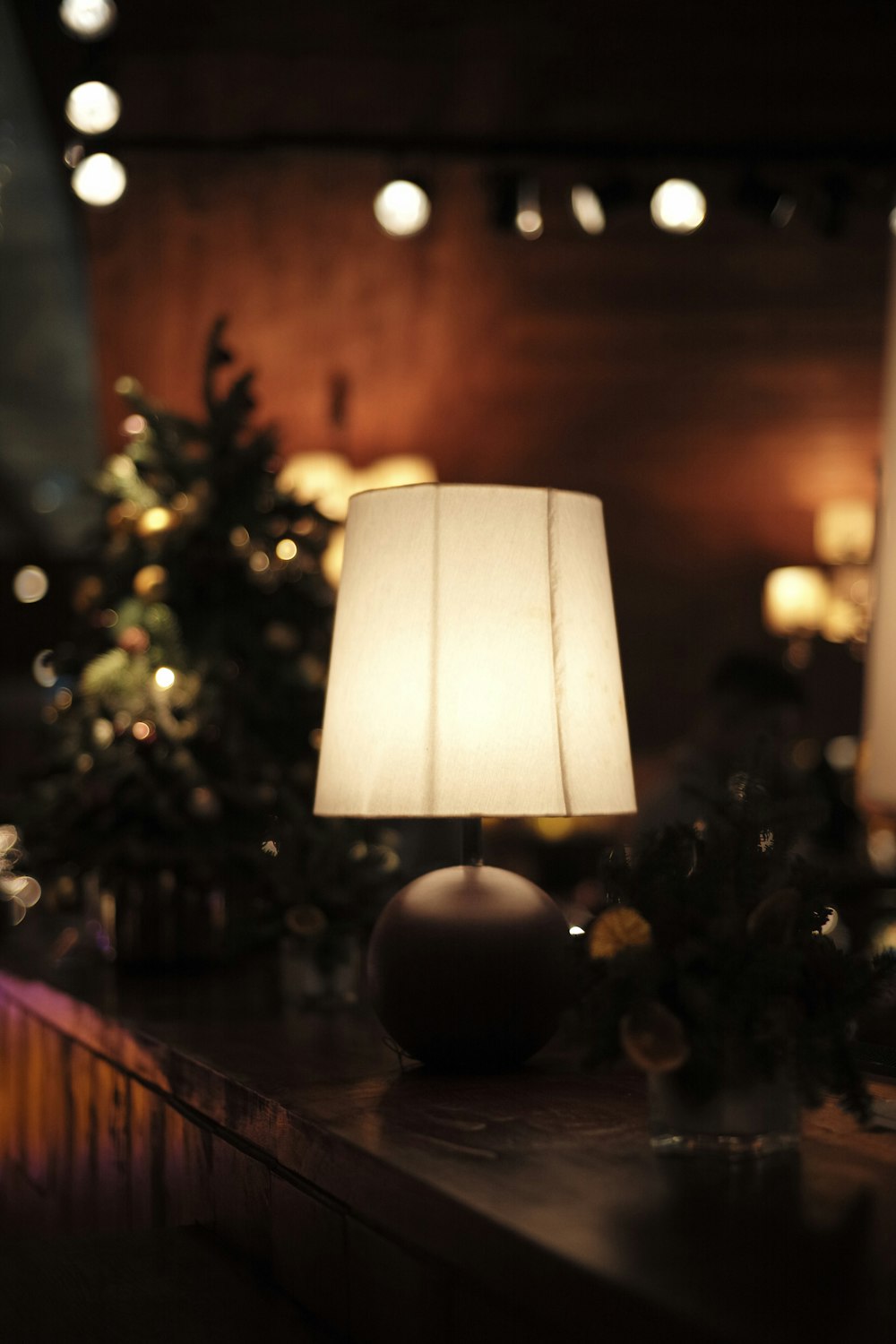 a table with a lamp on it and a christmas tree in the background