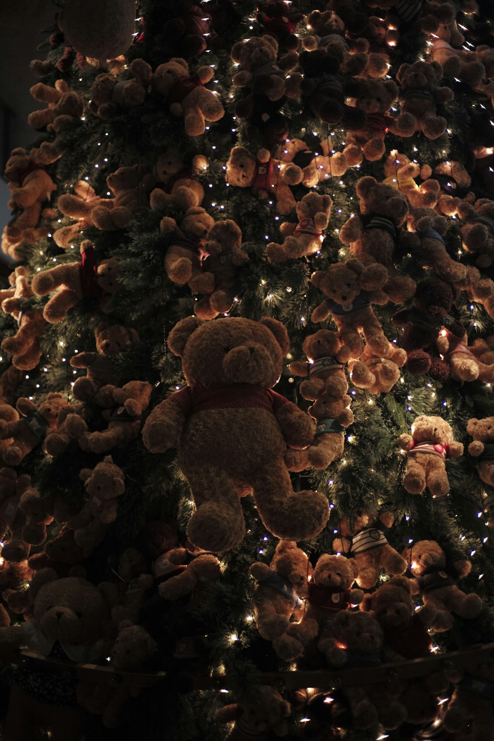 Um ursinho de pelúcia sentado em cima de uma árvore de Natal