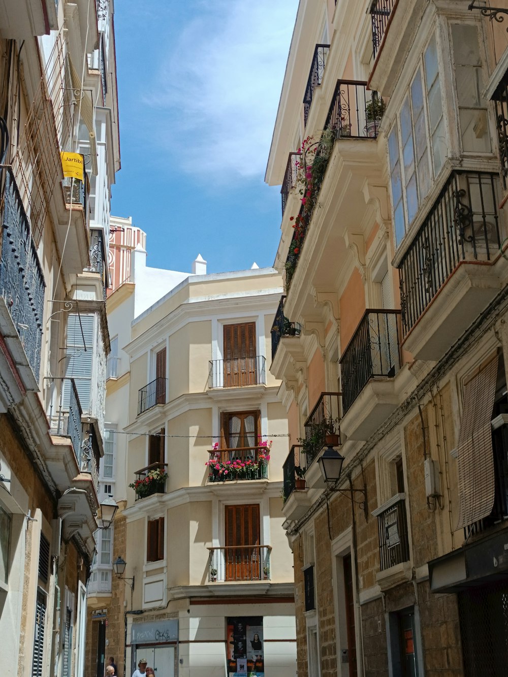 a narrow city street with people walking down it