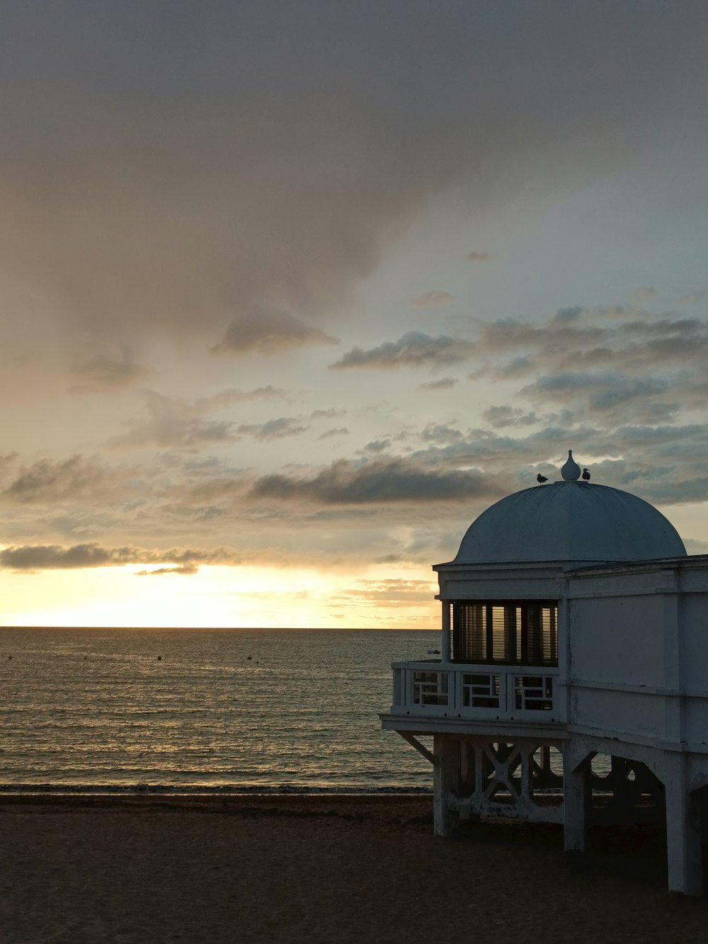 a white building sitting on top of a beach next to the ocean