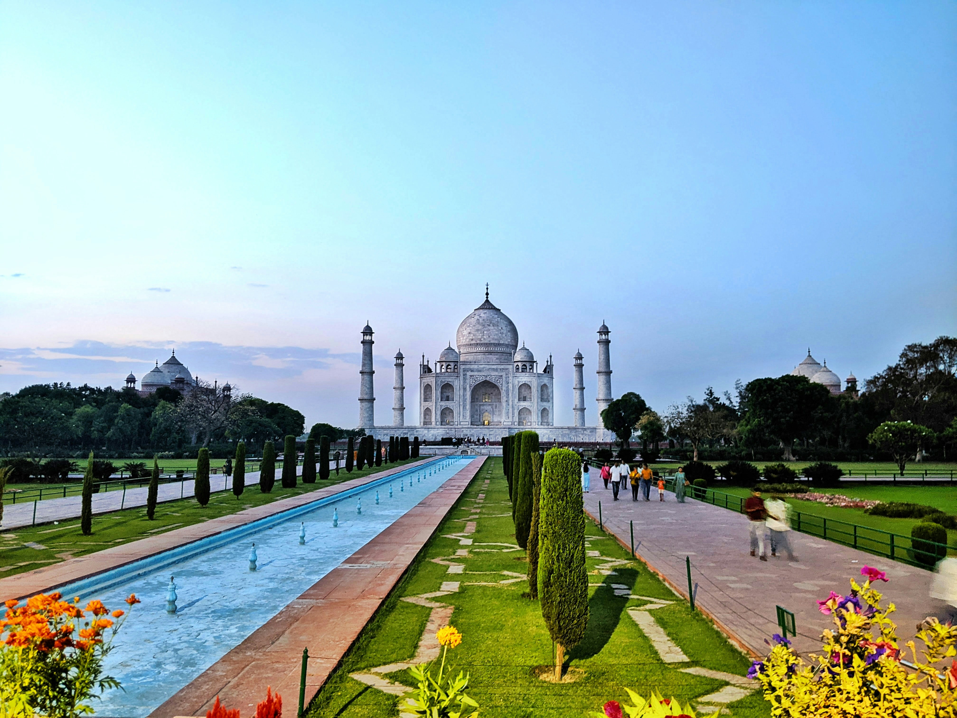 Taj Mahal at dawn with mist over reflecting pool, dark silhouetted gardens, moody atmospheric low-light, deep shadow on white marble