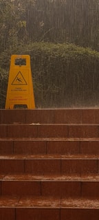 A friendly technician applying anti-slip treatment to outdoor stairs on a rainy day.