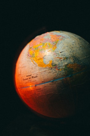 A globe displaying parts of North and South America with a warm red and orange light illuminating its surface. The text 'Naciones del Mundo' is visible on the globe, suggesting a Spanish label. The background is dark, emphasizing the glowing effect on the globe.